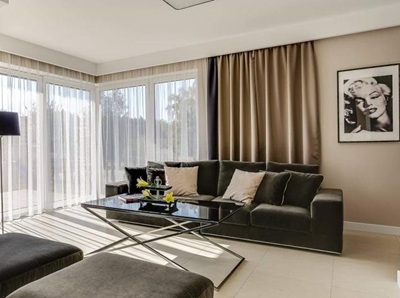 Modernes Wohnzimmer mit gro&szlig;en Fenstern, ma&szlig;gefertigten Gardinen und beigen Verdunkelungsvorh&auml;ngen